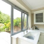 Thumbnail of http://A%20kitchen%20with%20light-colored%20cabinets,%20a%20sink,%20and%20a%20countertop%20opens%20to%20a%20garden%20through%20a%20large%20glass%20sliding%20door.