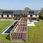 Thumbnail of http://Modern%20two-story%20house%20with%20solar%20panels%20and%20large%20glass%20windows,%20featuring%20a%20wooden%20pergola%20and%20rectangular%20pond%20in%20the%20landscaped%20backyard.