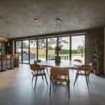 Thumbnail of http://Modern%20kitchen%20with%20a%20round%20dining%20table,%20leather%20chairs,%20and%20a%20potted%20plant%20centerpiece.%20Large%20windows%20offer%20a%20view%20of%20the%20garden.%20Barstools%20line%20the%20kitchen%20counter%20on%20the%20left.