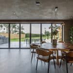 Thumbnail of http://Modern%20dining%20area%20with%20a%20wooden%20table%20and%20chairs,%20large%20windows,%20and%20a%20view%20of%20a%20grassy%20yard%20with%20outdoor%20seating.