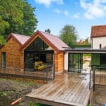 Thumbnail of http://Contemporary%20wooden%20pavilion%20with%20black%20bifold%20doors%20and%20glazing%20overlooking%20a%20stream,%20adjoining%20a%20Grade%20II%20listed%20historic%20building.
