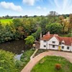 Thumbnail of http://Grade%20II%20listed%2015th%20century%20historic%20home%20with%20white%20rendered%20walls,%20terracotta%20roof%20tiles,%20positioned%20beside%20river%20with%20green%20pastoral%20fields%20beyond.