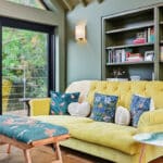 Thumbnail of http://Contemporary%20living%20room%20with%20yellow%20sofa%20and%20built-in%20shelving,%20accessed%20via%20black%20framed%20bifold%20doors%20opening%20to%20garden%20views%20and%20woodland%20landscape.