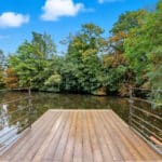 Thumbnail of http://Wooden%20deck%20with%20metal%20railings%20overlooking%20water%20and%20trees,%20exemplifying%20contemporary%20design%20in%20historic%20home%20renovation.