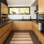 Thumbnail of http://Contemporary%20kitchen%20with%20wooden%20cabinetry,%20dark%20worktops,%20and%20black%20aluminium%20bifold%20doors%20framing%20views%20of%20Cornish%20landscape%20through%20large%20windows.