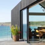 Thumbnail of http://Myrio%20Cornish%20coastal%20home%20with%20Sunflex%20bifold%20doors%20opening%20onto%20terrace%20overlooking%20Sennen%20Cove%20and%20turquoise%20seawater.