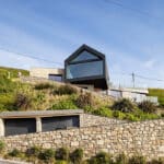 Thumbnail of http://Myrio%20Cornish%20home%20with%20black-framed%20glazing,%20stone%20walls,%20and%20green%20hillside%20setting%20overlooking%20Sennen%20Cove.