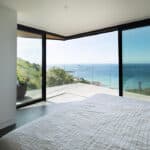 Thumbnail of http://Myrio%20Cornish%20home%20bedroom%20with%20expansive%20bifold%20doors%20opening%20onto%20terrace%20overlooking%20Sennen%20Cove%20and%20Atlantic%20Ocean.
